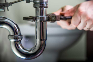 Preferred Home Solutions Plumber fixing sink pipe with a wrench