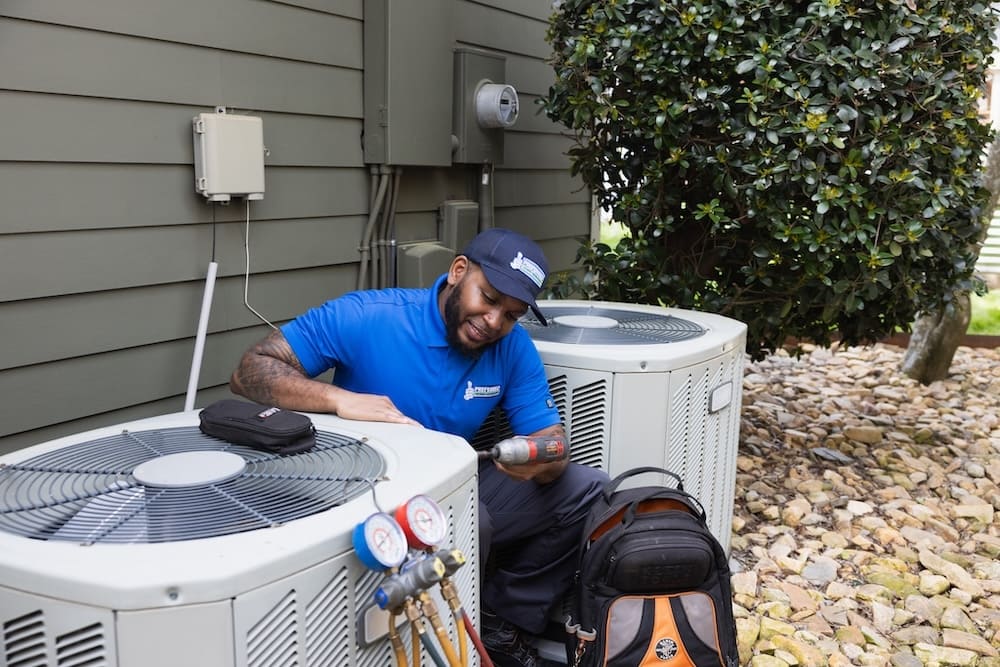 A professional Preferred Home Services technician verifies the connections on a new high-efficiency cooling system during a professional AC installation.