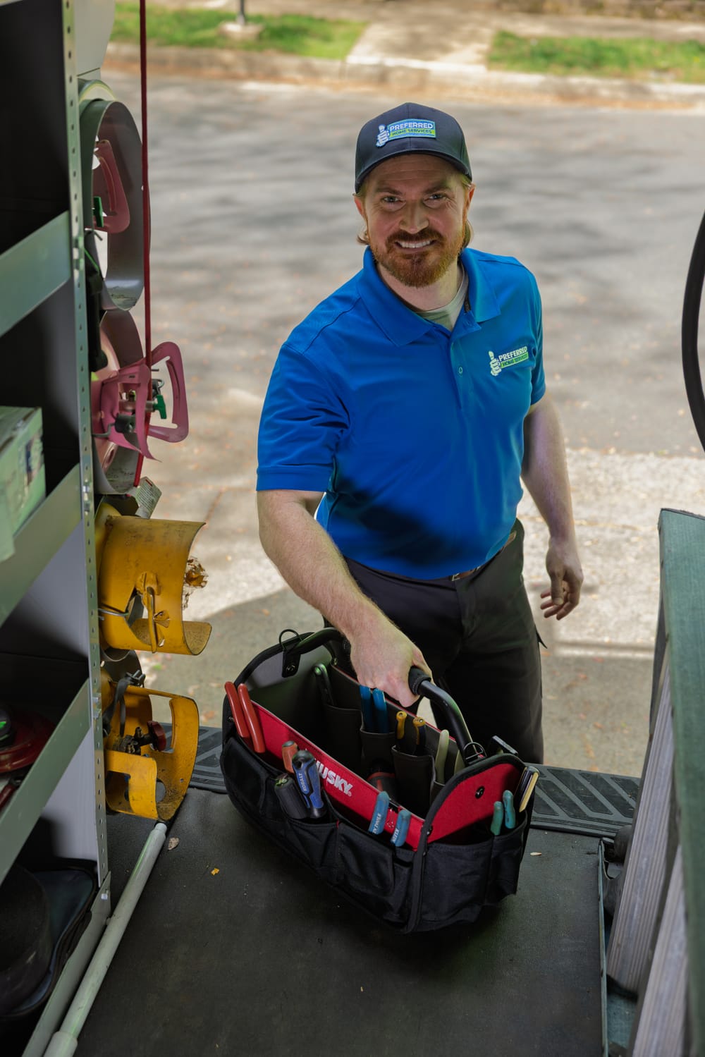 A professional Preferred Home Services technician prepares their equipment before entering a residence to provide expert heat pump services.