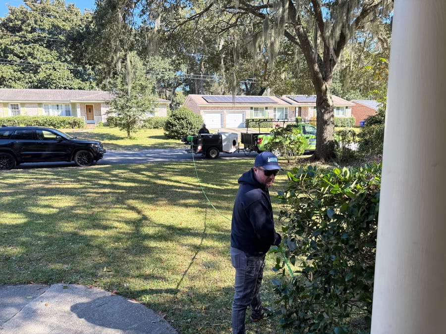 A Preferred Home Services plumber waves from a green service van as he arrives to provide professional hydro jetting and pipe cleaning services.