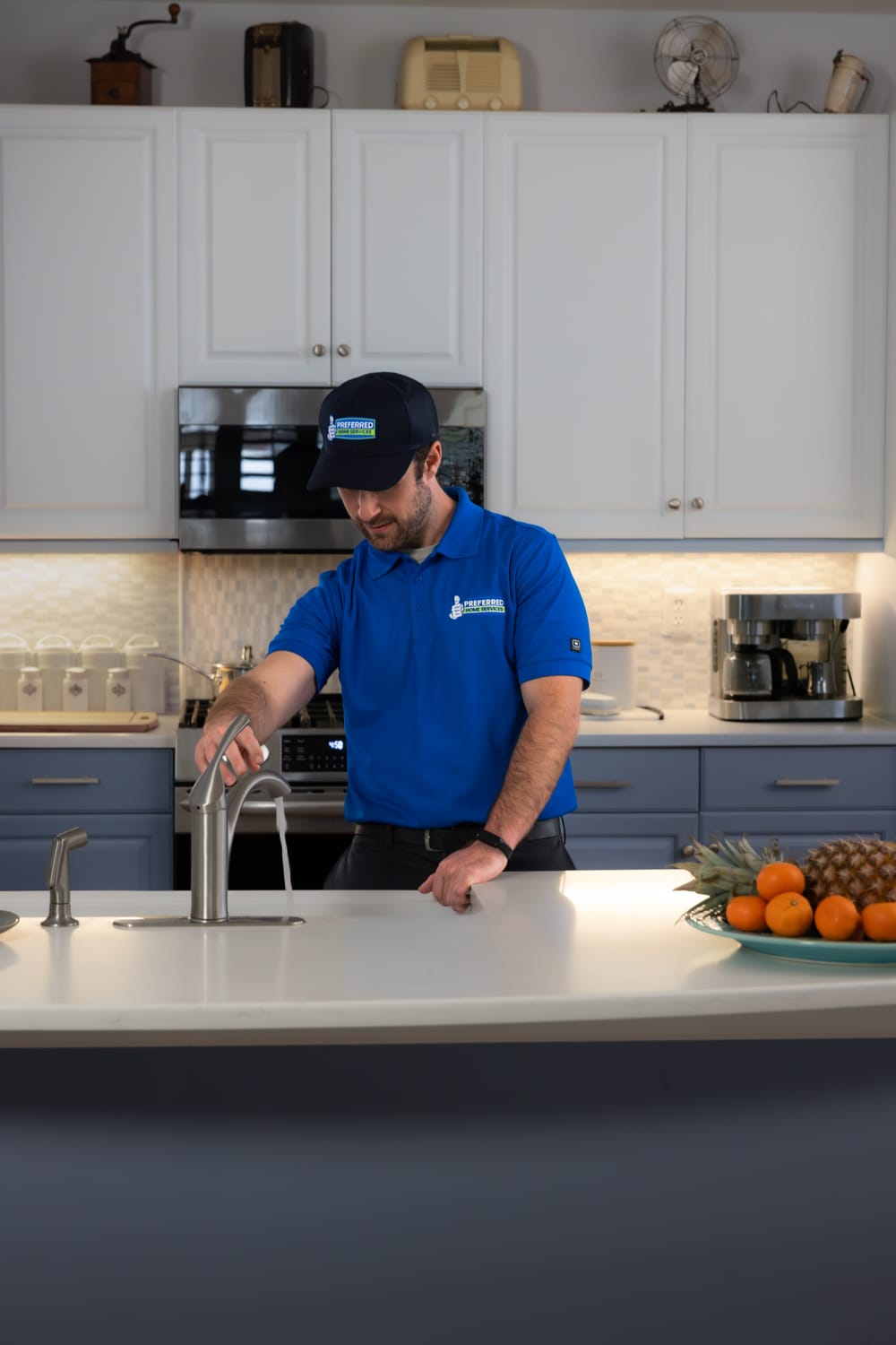 A Preferred Home Services technician performs a professional sink repair by inspecting a modern kitchen faucet to restore full functionality and ensure proper drainage.