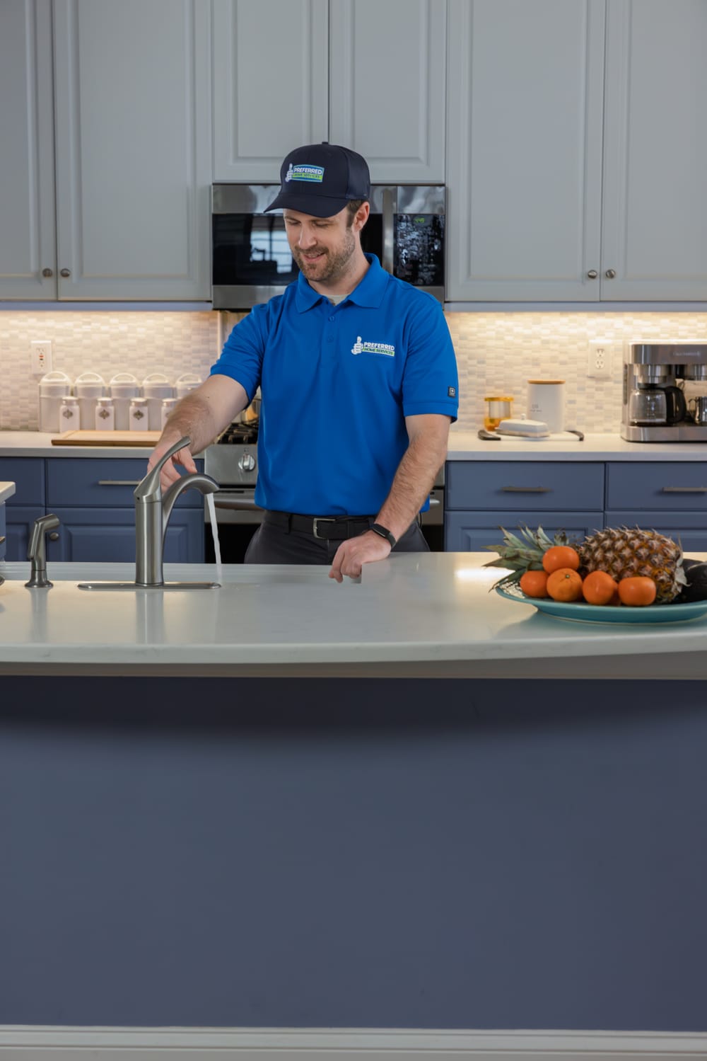 A Preferred Home Services technician tests the kitchen faucet flow in a modern home to verify the successful installation of a high-performance water filtration system.