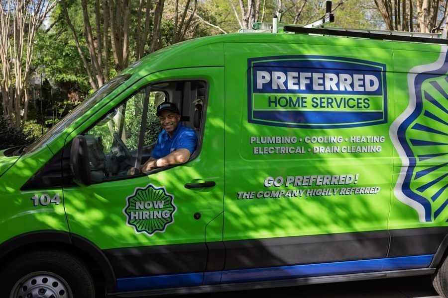 Green Preferred Home Services van with driver in blue shirt, advertising plumbing, cooling, heating, electrical, and drain cleaning; 'Now Hiring' sign visible.