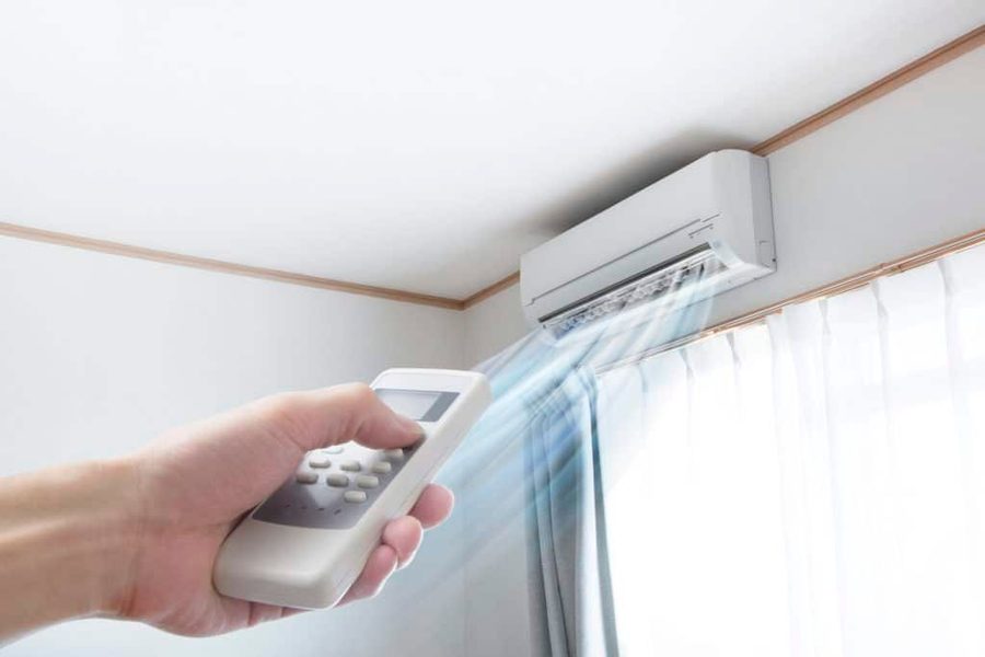 A homeowner uses a remote to control a wall-mounted mini-split air handler, illustrating a Preferred Home Services mini split repair and installation in South Carolina.