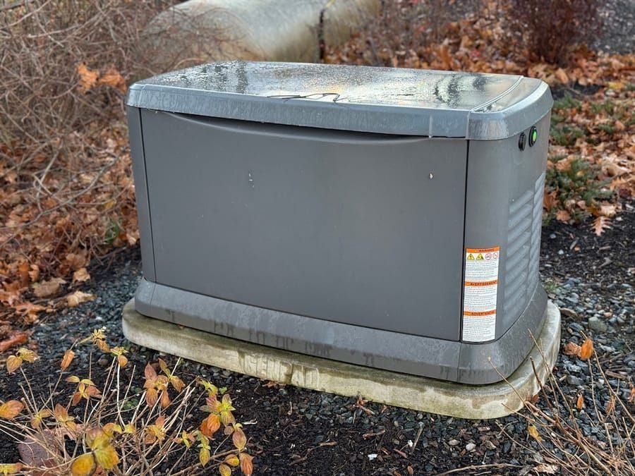 Outdoor hot tub with a lid, covered and water-streaked, on a concrete pad among autumn leaves.